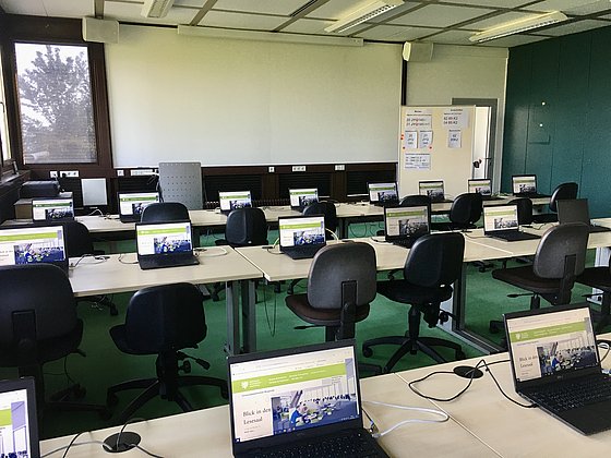 Foto vom Schulungsraum: Mehrere Tischreihen mit aufgeklappten Laptops